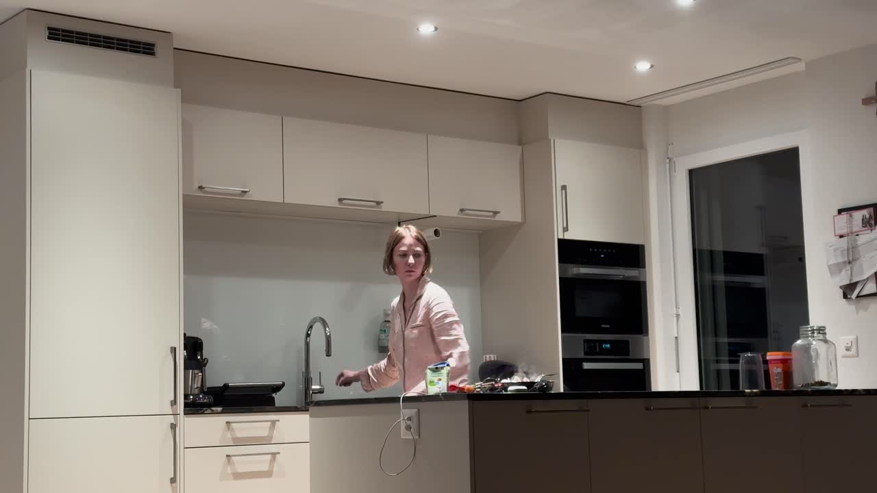 Una donna prepara uno spuntino a tarda notte in una cucina moderna. Concetto di fame notturna, comfort domestico, stile di vita quotidiano e cucina informale di notte