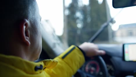 close up from behind of a mature man driving a car in rainy day