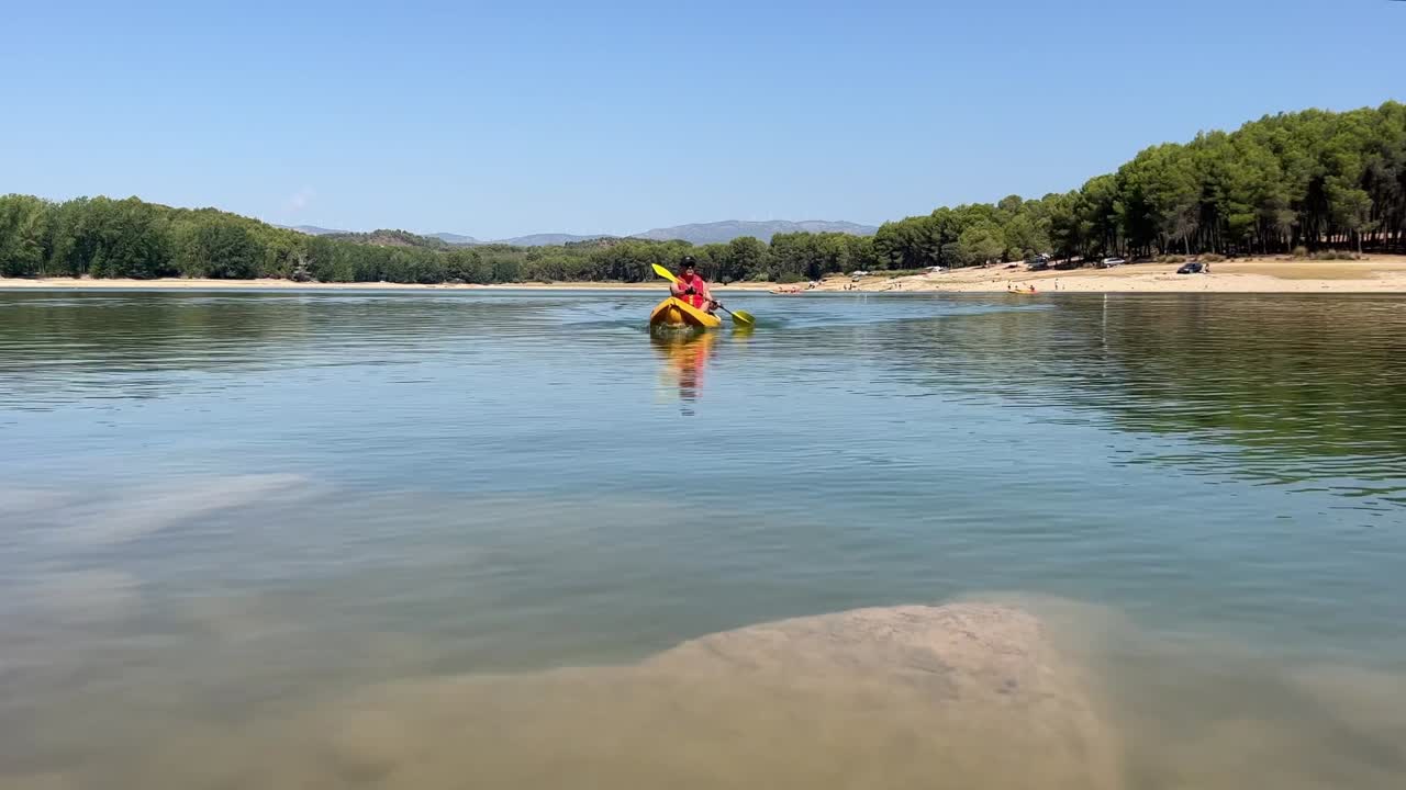 белый мужчина среднего возраста в желтом каяке гребёт в озере