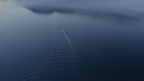 tilt up shot of fishing boat in kotor bay during misty morning, aerial