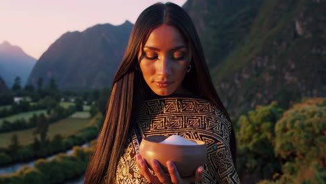 woman in traditional attire with a bowl during sunrise/sunset ceremony in the mountains
