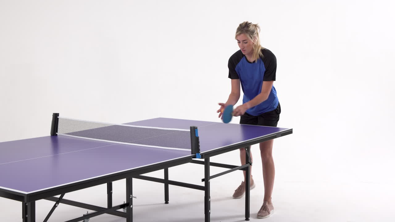 Female table tennis player serving and passing the ball on white background, copy space