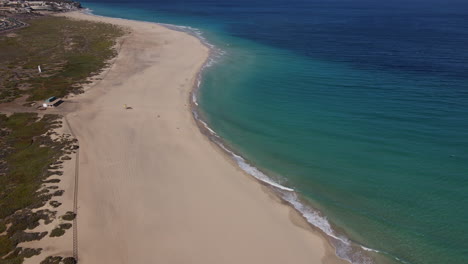 Fantastica-Toma-Aerea-De-La-Playa-De-Morro-Jable,-Recorriendo-La-Playa-De-Aguas-De-Un-Azul-Intenso