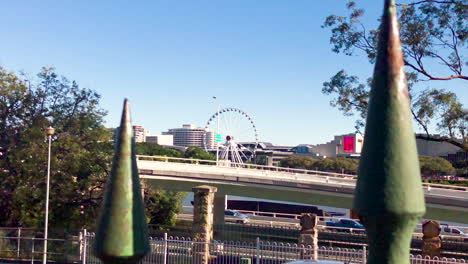 close up of green iron fence with the wheel of brisbane in distance