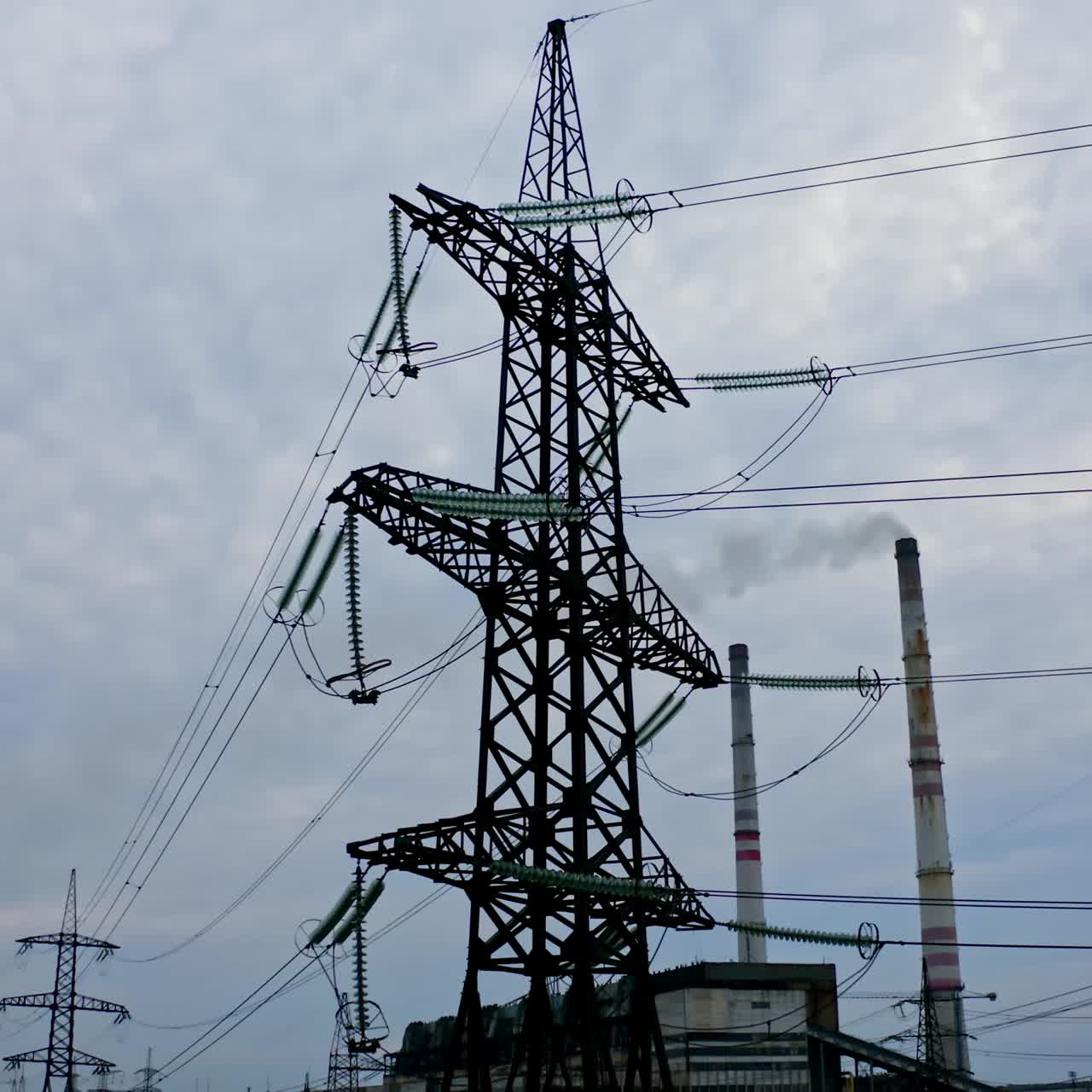 Electricity pylons and high-voltage power lines on the green grass. Power plant. Electrical power grid. View from the top