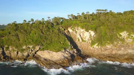 toma aérea volando hacia la trilha da sepultura a la hora dorada en bombinhas, brasil