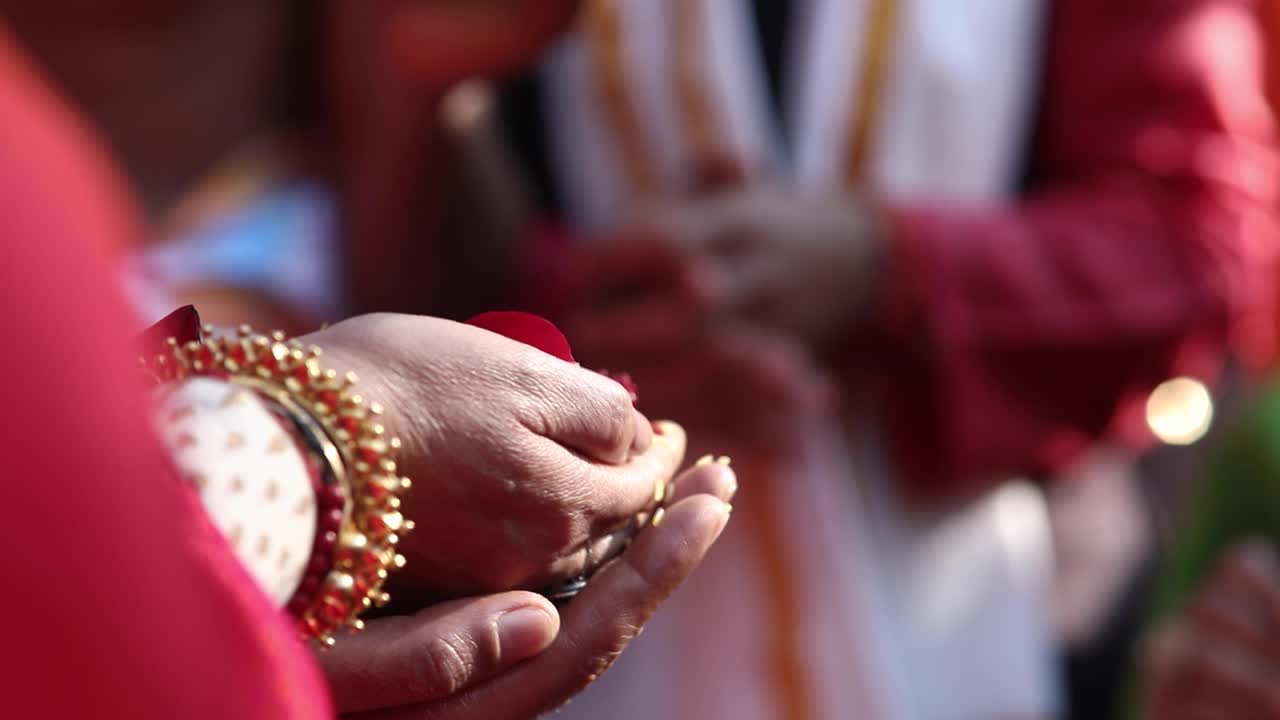 Mani di un'anziana signora indiana che tengono petali di fiori durante una sacra cerimonia religiosa indù.