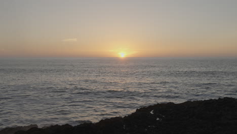 Waves-hitting-the-rocks-creating-a-water-splash-during-the-sunset-in-Ericeira,-Portugal