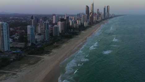 Aerial-drone-flyover-Broadbeach-gold-coast-capturing-long-stretched-sandy-beach-with-waves-crashing-the-shore,-luxury-waterfront-apartments-and-ocean-views-resort-hotels