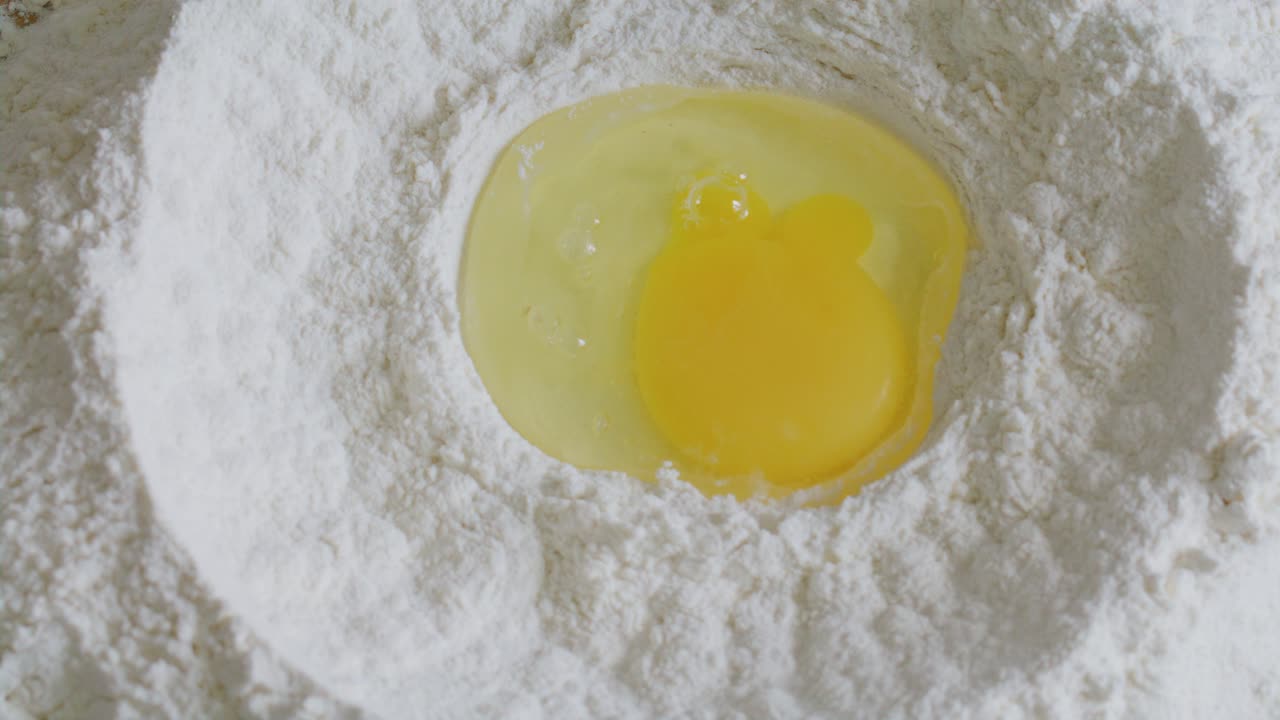 Pouring Egg into Well in Flour for Dough Preparation