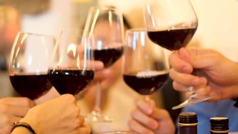 young adults toast as their red wine glasses clink together followed by a drink