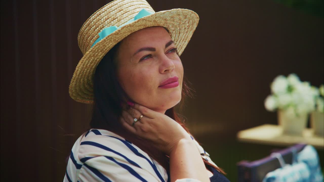 Woman in straw hat enjoying sunny day outdoors with soft sunlight illuminating her face