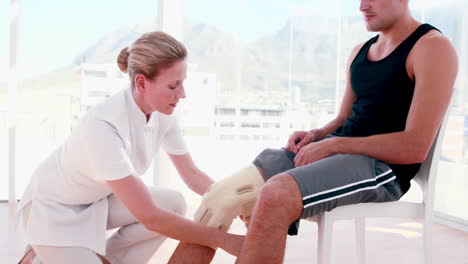 el médico examinando la rodilla de su paciente