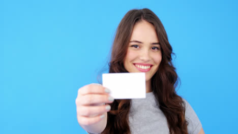 beautiful woman holding blank visiting card on blue background