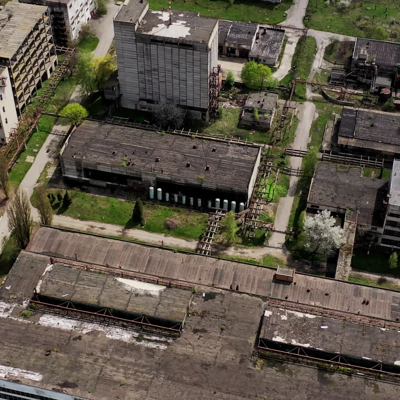 Rusty destroyed roofs of abandoned factory buildings. Empty ruined territory of a factory in spring. Aerial view