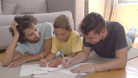 Two-fathers-helping-focused-boy-with-home-task