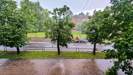 a view of pouring rain outside the street with road traffic. static shot