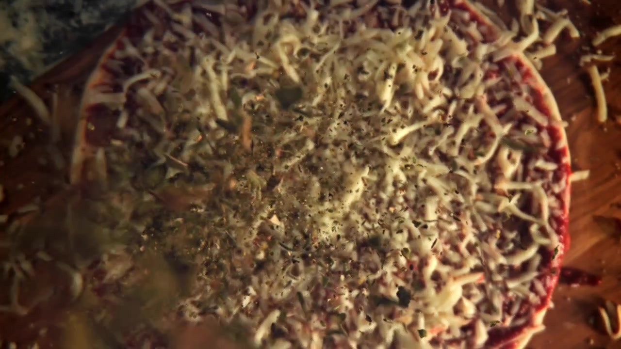Rallentatore di erbe aromatiche e spezie che si spargono su pizza cruda