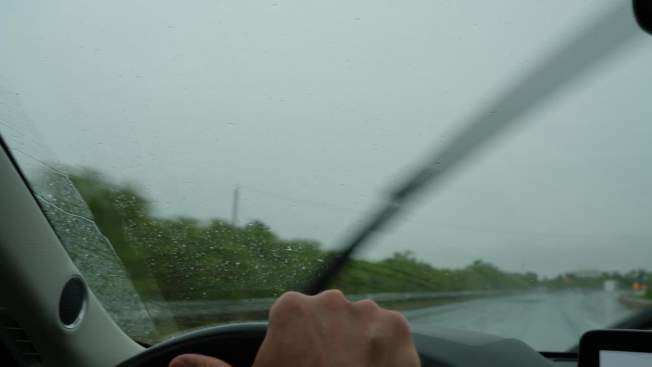 Driver navigating highway in heavy rain with active wipers