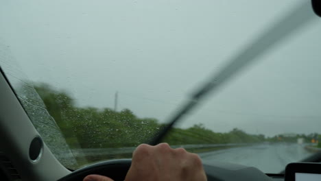 driver navigating highway in heavy rain with active wipers