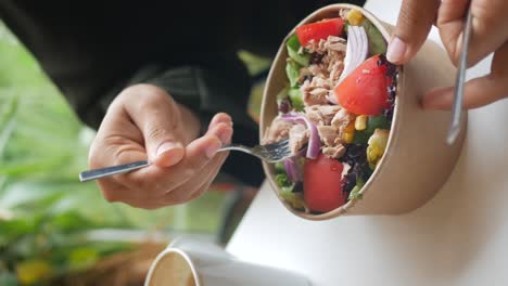 persona que come ensalada de atún