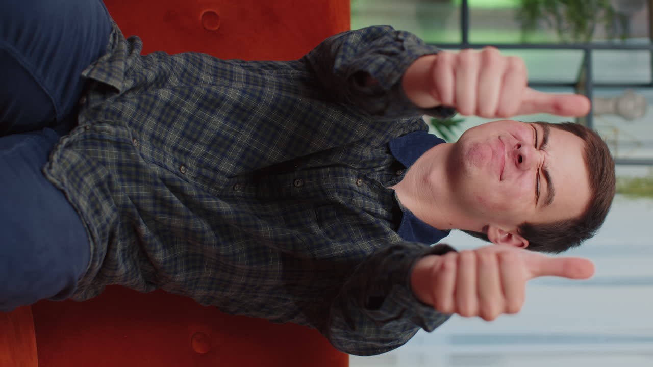 행복한 젊은 십대 남자가 카메라를 승인하며 긍정적인 징조, 좋은 소식을 보여주는 엄지손가락을 보여주고 있습니다.