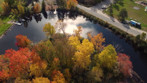 flying over colourful treetops descending towards mirrorlike surface of doe lake