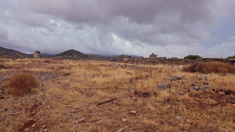 distant windmills stand among rocky terrain in a gray landscape at dusk