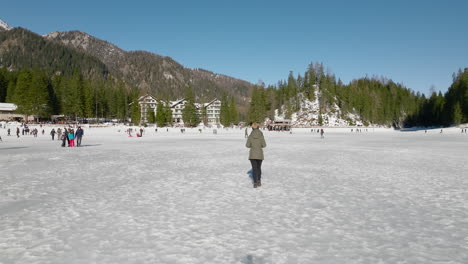 woman from behind walking on a snowy and mountainous terrain