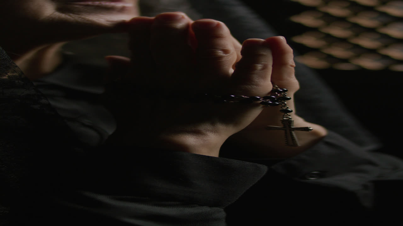 Close-Up of Elderly Woman Holding Rosary and Praying in Confessional Booth
