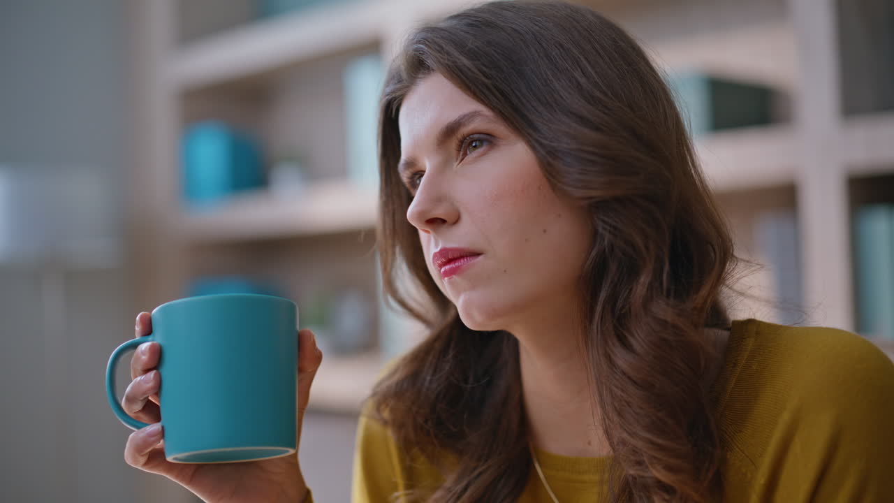 Thoughtful woman drinking coffee at modern home interior closeup portrait
