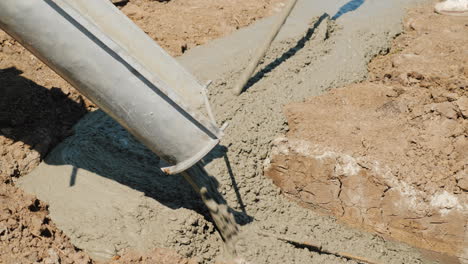 el hormigón fluye a través de la tubería hacia los cimientos del concepto de construcción de cabañas en el sótano