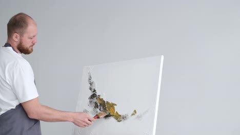 young talented artist working on abstract painting uses paint brush to create picture working in - young talented artist working on abstract painting, uses paint brush to create picture. working in dark creative studio with large canvas and easel. copy space