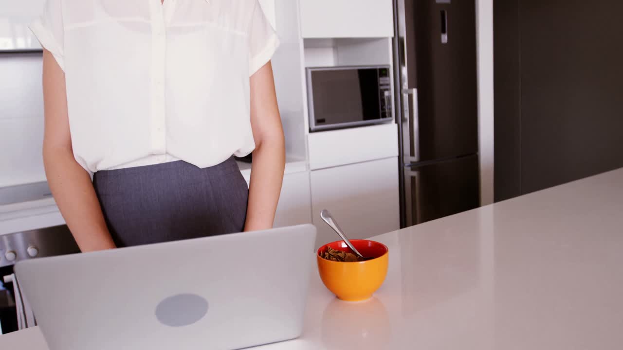 Donna che utilizza computer portatile nella cucina