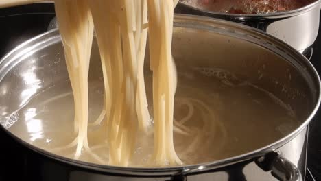 cooking spaghetti  in boiling water in a metal pan