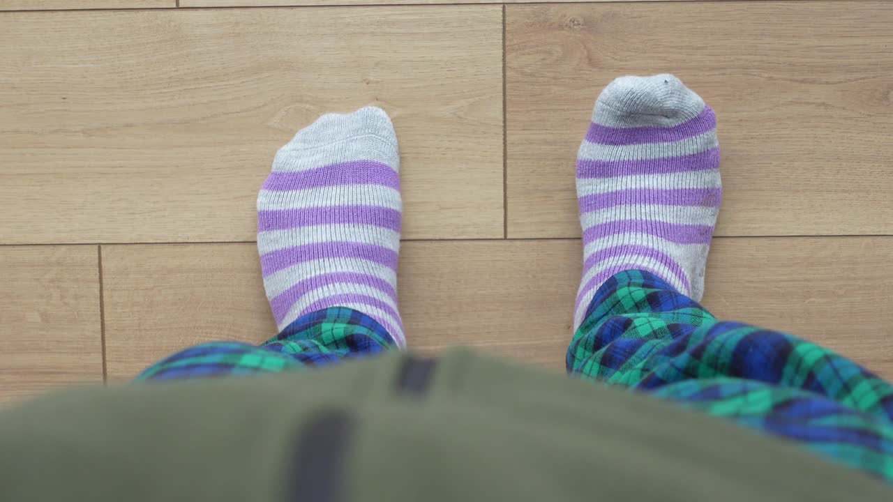 Person Standing in Striped Socks and Plaid Pants on a Wooden Floor