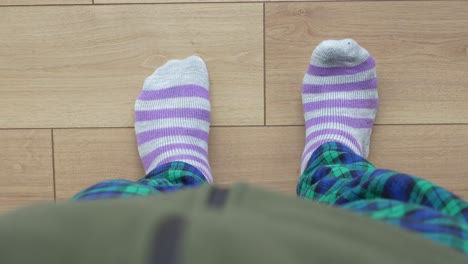 person standing in striped socks and plaid pants on a wooden floor