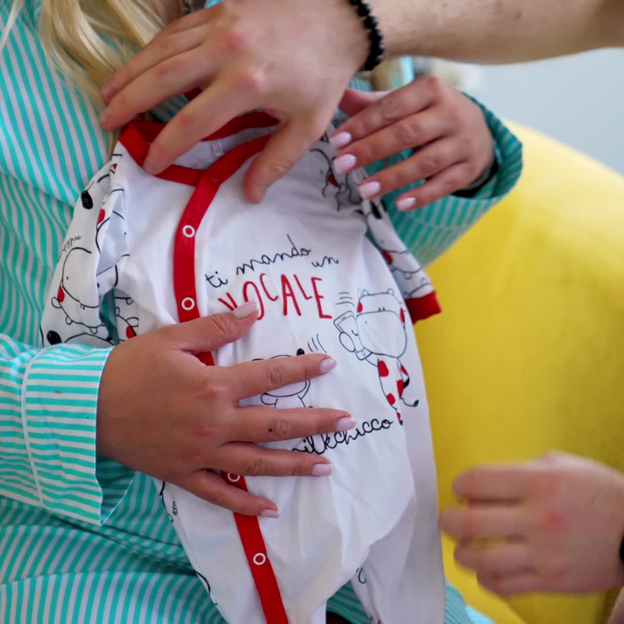 Future daddy takes a little baby romper. Man puts the child's clothes on the pregnant belly of his wife