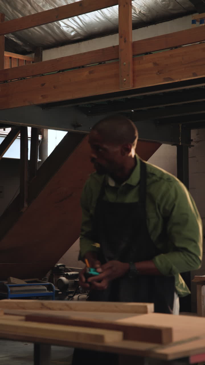 Vertical video: African American carpenter in shop receiving square marking wood, assembling frame