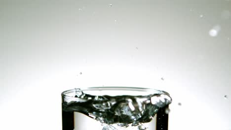 Ice-cube-falling-into-glass-of-water