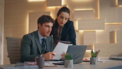 office team watching papers working together at computer workplace closeup