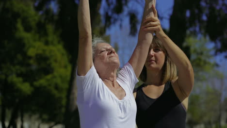 focused elderly woman training with cheerful personal coach.