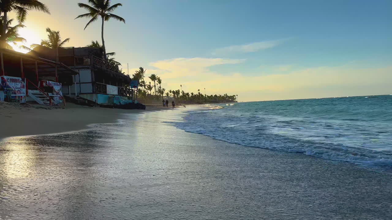 Fale rozbijające się o progi prymitywnych sklepików plażowych podczas przypływu na Punta Cana, Dominika, wyspa Hispaniola