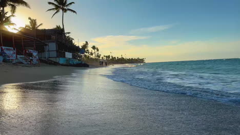 waves-rolling-to-the-doorstep-of-the-primitive-beach-shops-at-high-tide-on-Punta-Cana,-Dominican,-Hispaniola-island