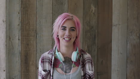 retrato de una joven punk de una mujer bonita con un peinado rosa sonriendo feliz mirando a la cámara fondo de madera tatuaje de arte corporal femenino urbano independiente