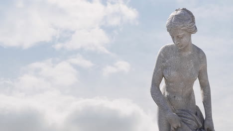 animation of gray sculpture of woman over blue sky and clouds, copy space