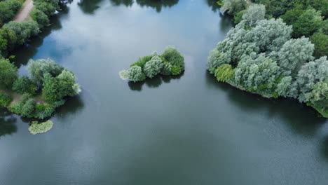 Close-up-of-little-island-in-alderson-lake-with-still-water-reflection-in-Needham-market