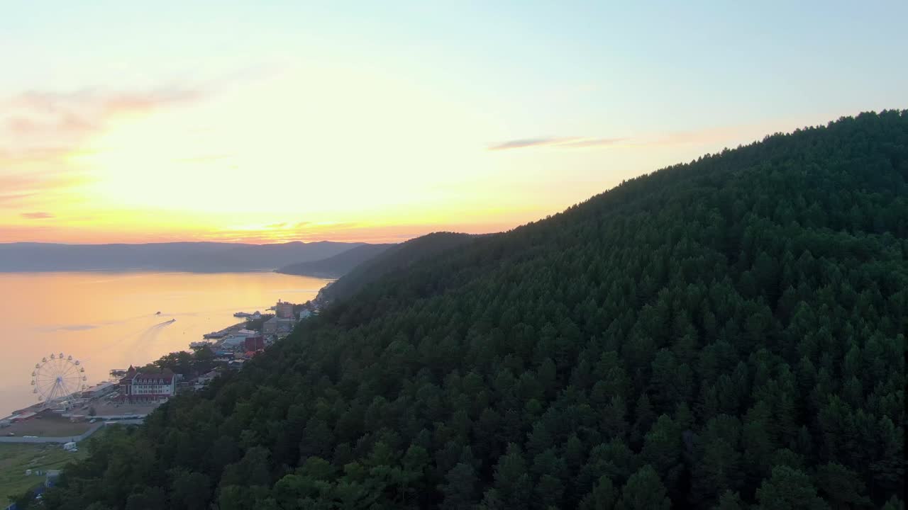 Solnedgang over en sø og et bjerg med skov