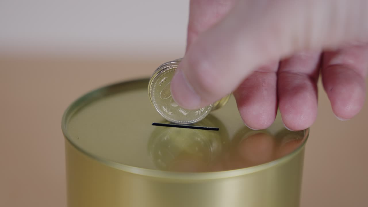 Coins being added to gold tin can by hand in slow motion, Savings concept