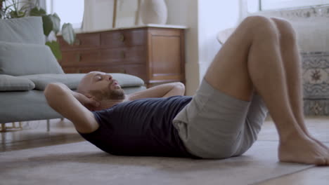 concentrated caucasian man exercising on floor at home